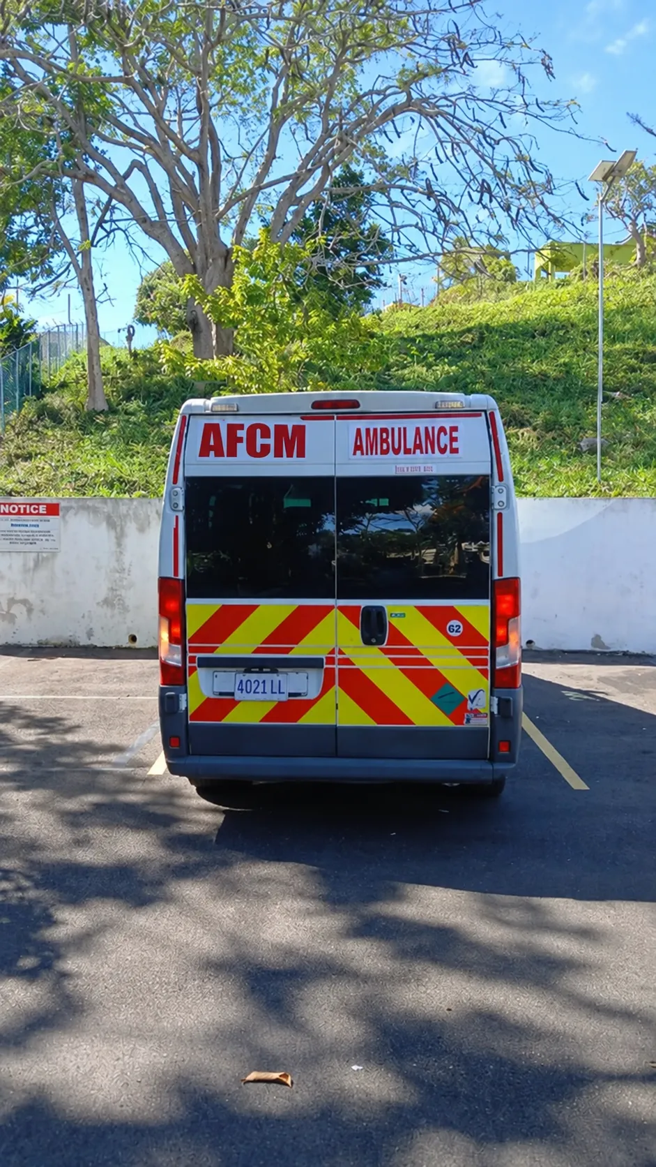 Rear view of an AFCM ambulance with reflective chevron markings, parked at an AFCM location in Jamaica